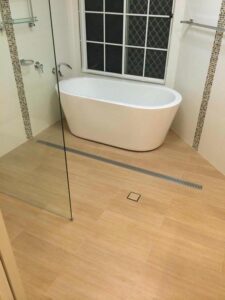 En-suite with freestanding bath and wood-look tiles on floor