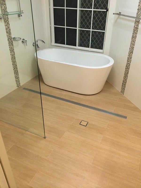 En-suite with freestanding bath and wood-look tiles on floor