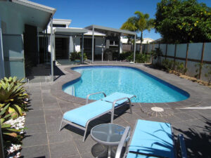 Outdoor space with skillion roof BBQ area and a central swimming pool. Basalt tiled pool surrounds.