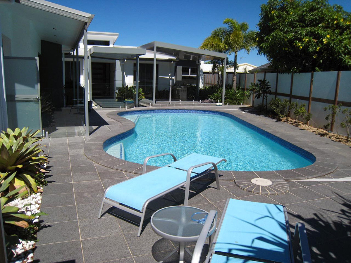 Outdoor space with skillion roof BBQ area and a central swimming pool. Basalt tiled pool surrounds.
