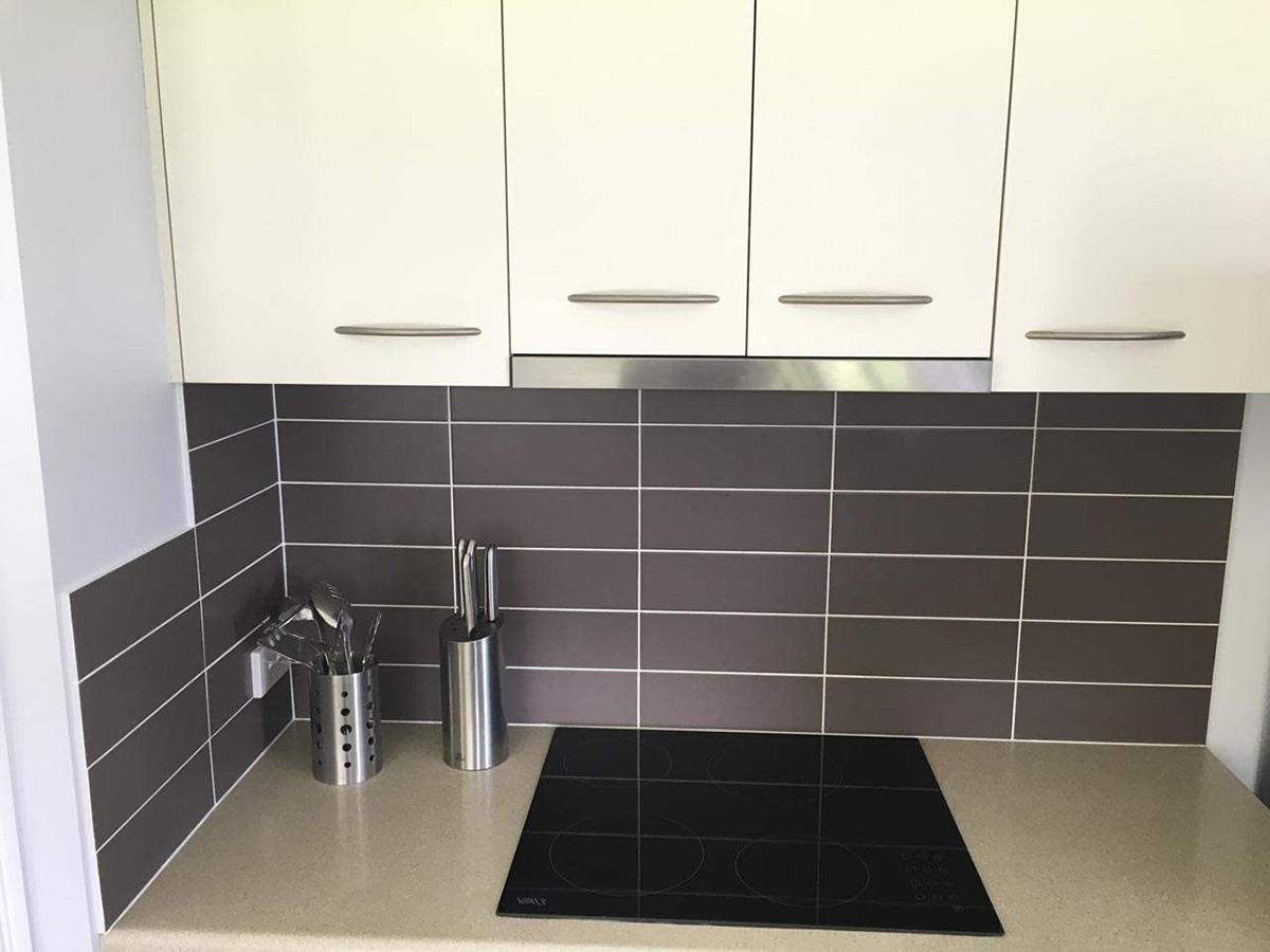 Kitchenette with a 4 element cook-top and subway tiled backsplash