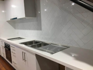 Kitchen under a staircase with white subway tiles in a Herringbone pattern