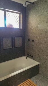Shower bath area with dark grey tiles throughout